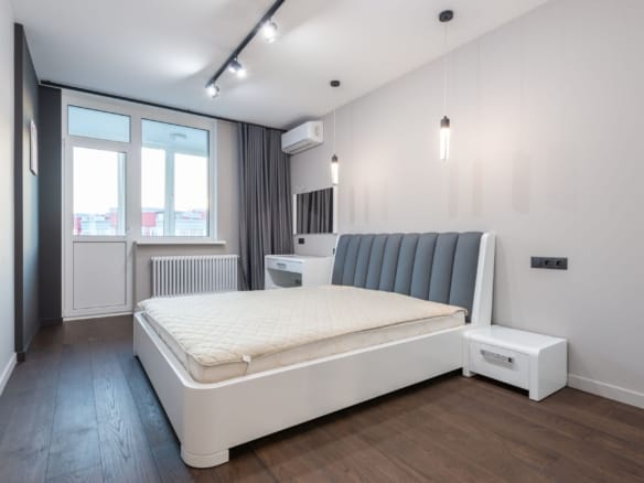 Spacious minimalist bedroom featuring modern design elements with white walls and parquet flooring. — Newport Beach real esta