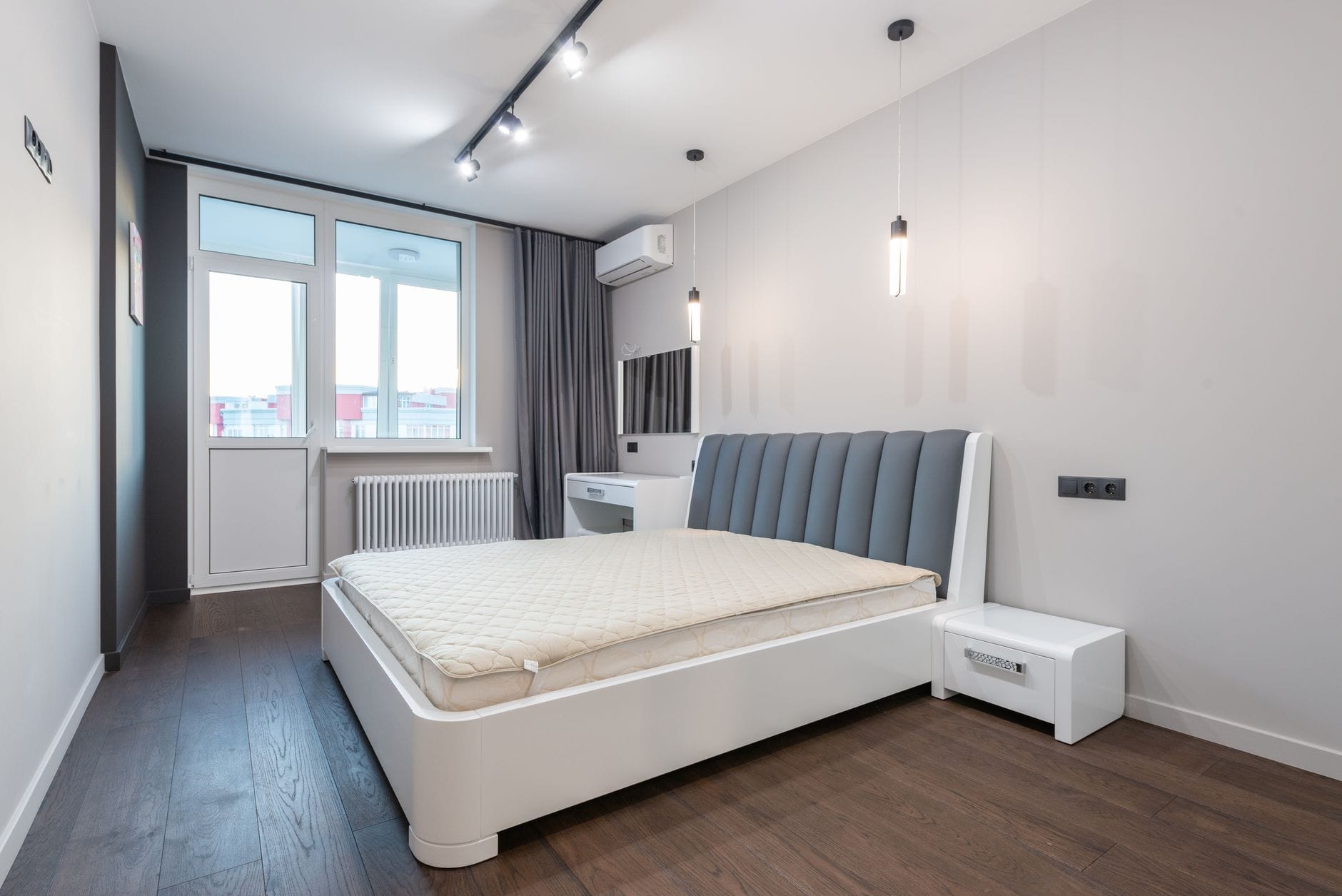 Spacious minimalist bedroom featuring modern design elements with white walls and parquet flooring. — Newport Beach real esta